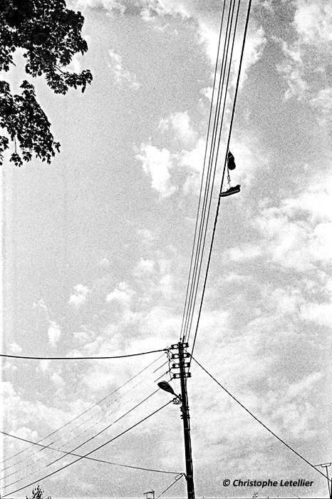 Photo en noir et blanc d'une paire de baskets accrochée par ses lacets sur les fils electriques d'une rue de Gisors (Eure).© 2015 Christophe Letellier all rights reserved. 