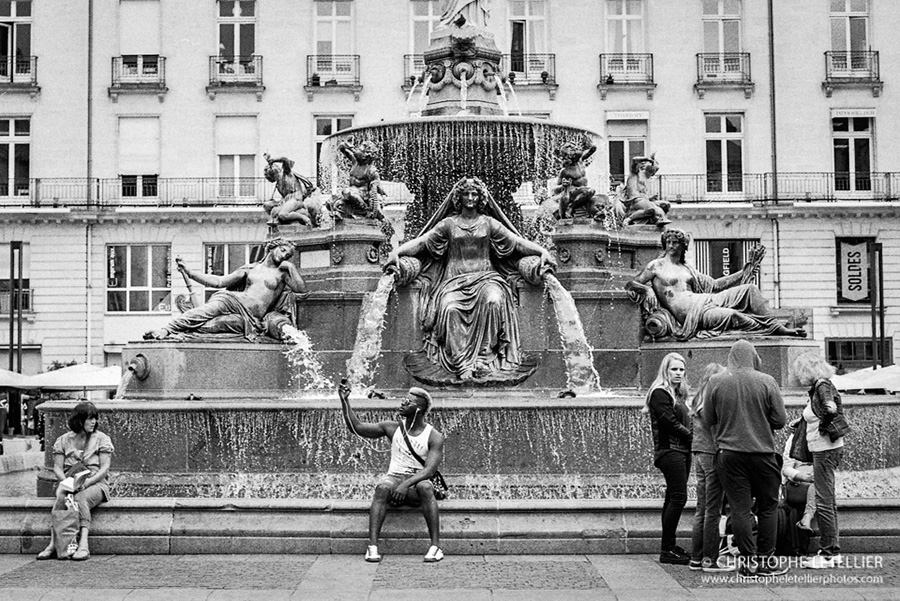 Photo en noir et blanc d'un jeune homme noir realisant un selfie à la fontaine place royale à Nantes en Loire-Atlantique. © 2016 Christophe Letellier all rights reserved. 