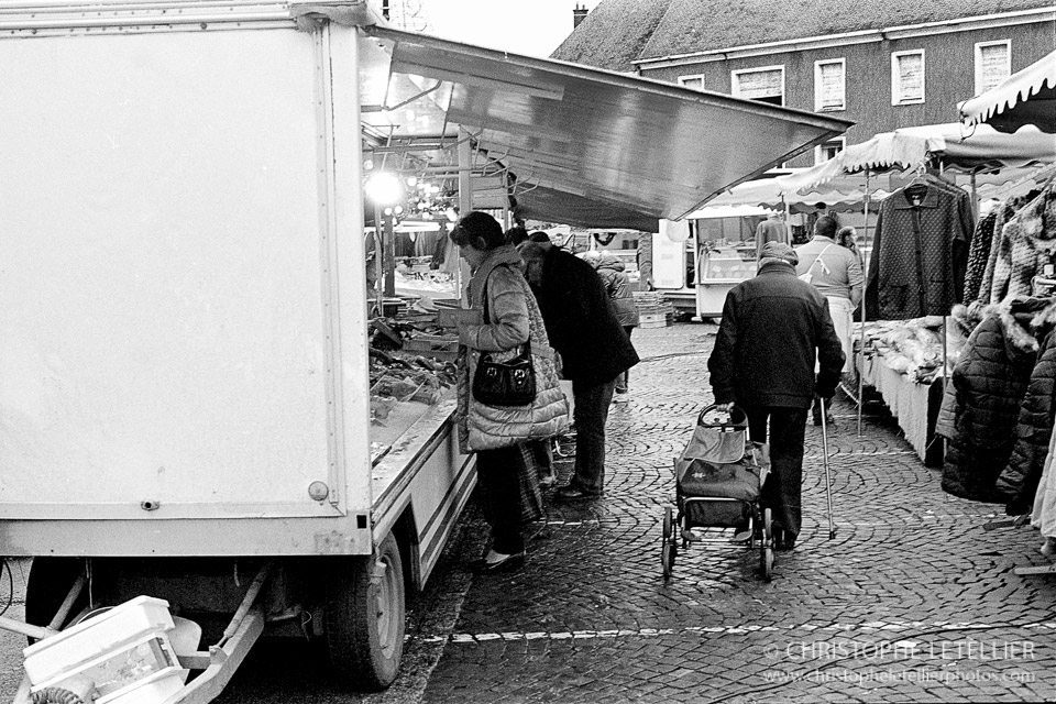 Photo en noir et blanc d'un vieil homme faisant ses courses durant le marché hebdomadaire du vendredi de Gisors. Un marché essentiellement alimentaire à base de vente de poissons, fruits et légumes. © 2016 Christophe Letellier all rights reserved. 