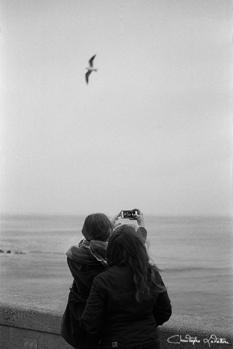 Photo en noir et blanc de jeunes femmes utilsant un smartphone pour realiser un selfie à la plage de Granville © 2016 Christophe Letellier all rights reserved. 