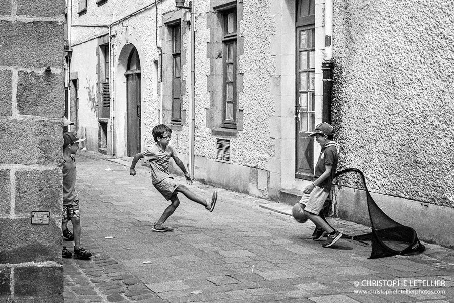 Photo en noir et blanc de jeunes enfants jouant au football dans une petite rue du Croisic. © 2016 Christophe Letellier all rights reserved. 