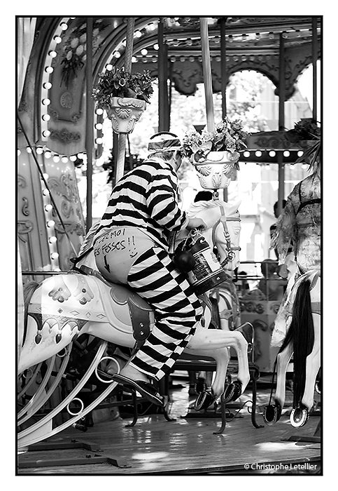 "ENTERREMENT DE VIE DE GARCON". Photo d'un homme déguisé en prisonnier sur un manège de chevaux de bois à Montélimar, ville de la Drôme célèbre pour son fameux Nougat de Montélimar. © 2010 Christophe Letellier tous droits réservés.